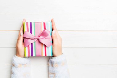 Kadın ellerinin Noel 'i ya da diğer tatil el yapımı hediye paketlerini avuçlarında tutuşu, fotokopi alanı olan düz masa arkaplanı.