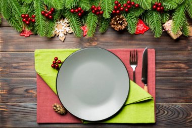 Çatal bıçak takımının ve tabağın en üst görüntüsü şenlikli ahşap arka planda. Yeni yıl aile yemeği konsepti. Firavun ağacı ve Noel süslemeleri