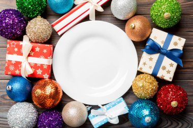 Ahşap arka planda tatil ayarlarının en üst görüntüsü. Tabak, hediyeler, mücevherler ve Noel süslemeleri. Yeni yıl yemeği konsepti