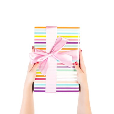 Kadın eli, paketlenmiş Noel veya diğer tatil hediyelerini pembe kurdeleli renkli kağıda sarar. Beyaz arkaplanda izole edilmiş, üst manzara. Şükran Günü hediye kutusu konsepti