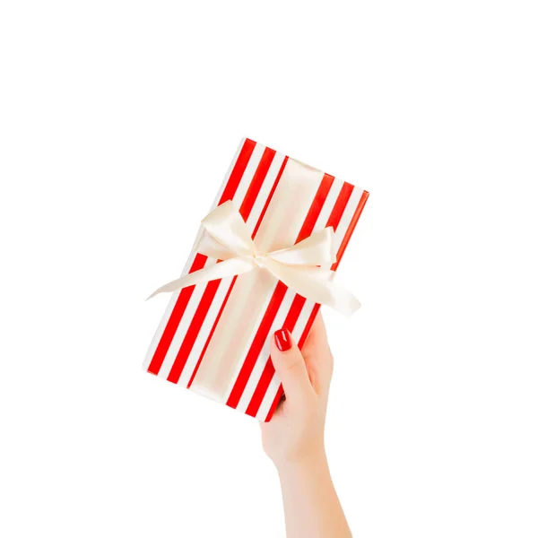 Vrouw handen geven verpakt Kerstmis of andere vakantie met de hand gemaakt in rood papier met gouden lint. Geïsoleerd op witte achtergrond, bovenaanzicht. dankzegging Geschenkdoos concept — Stockfoto