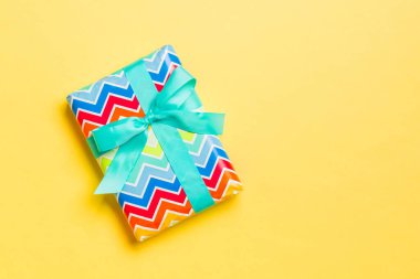 Noel ya da yeni yıl için mavi fiyonklu hediye kutusu sarı arka planda, fotokopi alanı olan üst manzara