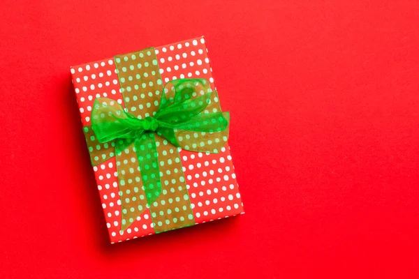 Gift box with green bow for Christmas or New Year day on red background, top view with copy space — Stock Photo, Image