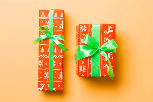 Envuelto Navidad u otro regalo hecho a mano de vacaciones en papel con cinta verde sobre fondo naranja. Caja de regalo, decoración de regalo en mesa de colores, vista superior —  Fotos de Stock
