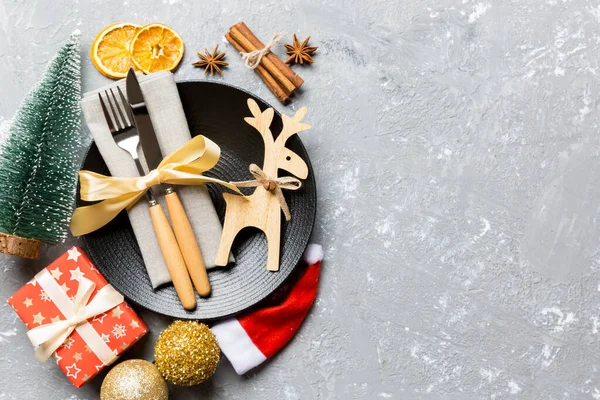 Vista superior de la cena navideña decorada con fruta seca y canela sobre fondo de cemento. Conjunto de decoraciones de plato, urensil y Año Nuevo. Concepto navideño con espacio epmty para tu diseño — Foto de Stock