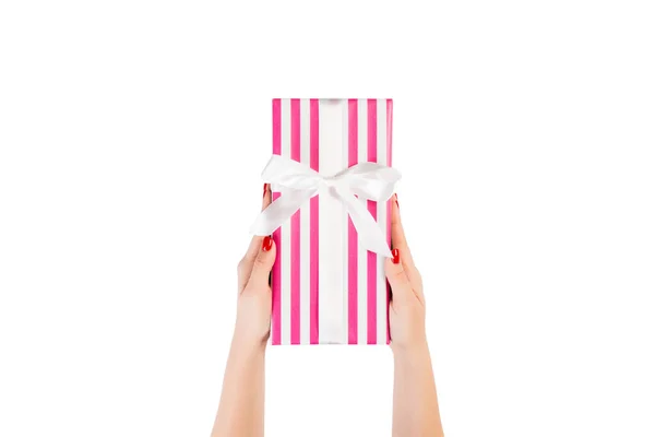 Vrouw handen geven verpakt Kerstmis of andere vakantie met de hand gemaakt in roze papier met wit lint. Geïsoleerd op witte achtergrond, bovenaanzicht. dankzegging Geschenkdoos concept — Stockfoto