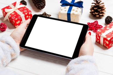 Hediye kutularından yapılmış ahşap Noel arka planında bir tablet tutan kadınların üst görüntüsü. Yeni yıl tatili konsepti. Model