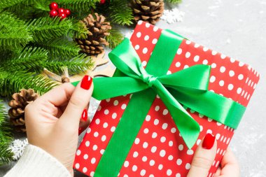 Bir kadının elinde hediye kutusuyla şenlikli çimento arka planına baktığı en iyi manzara. Firavun ağacı ve Noel süslemeleri. Yeni yıl zaman kavramı