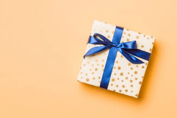 Top pohled vánoční dárek box s modrým lukem na oranžovém pozadí s kopírovacím prostorem — Stock fotografie