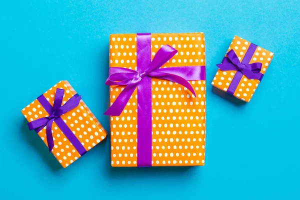 Verpakt Kerstmis of andere met de hand gemaakte vakantie cadeau in papier met paars en roze lint op blauwe achtergrond. Aanwezig doos, decoratie van cadeau op gekleurde tafel, bovenaanzicht — Stockfoto