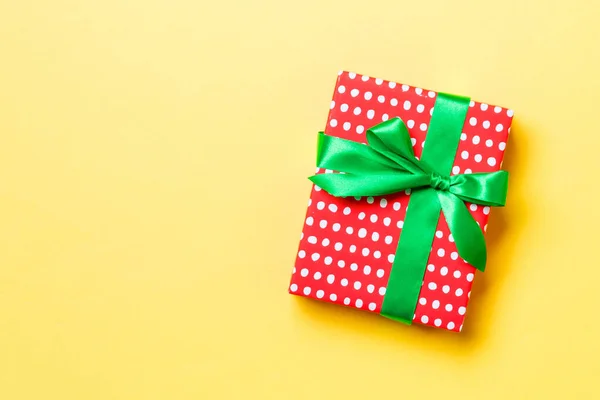 Envuelto Navidad u otro regalo hecho a mano de vacaciones en papel con cinta verde sobre fondo amarillo. Caja de regalo, decoración de regalo en mesa de colores, vista superior con espacio para copiar —  Fotos de Stock