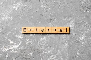 Tahta blokta EXTERNAL kelimesi yazıyor. Deksing, konsept için EXTERNAL metin çimento tablo üzerinde.