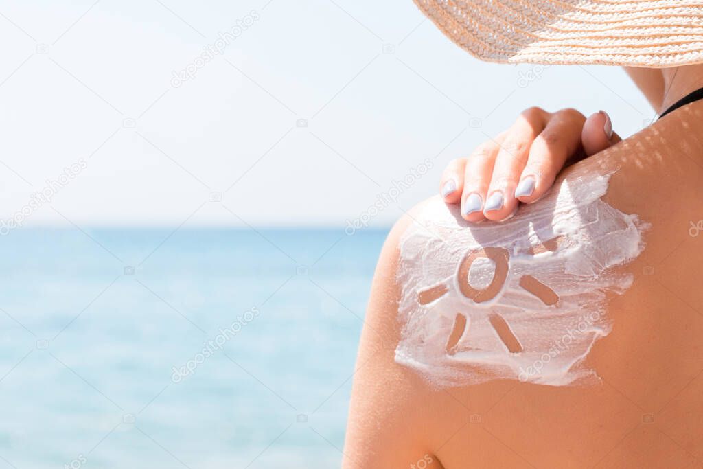 Sunscreen lotion in sun shape on tanned woman's shoulder.