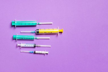 Mor arkaplanda farklı şırıngaların üst görünümü. Kopya alanı ile tıbbi enjeksiyon kavramı.