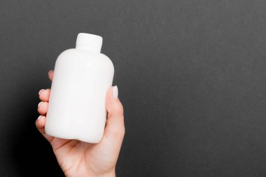 Siyah arka plan, kadın eli kozmetik şişesi ve tasarımınız için kopyalama alanı..