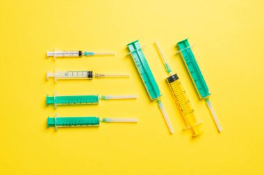 Sarı arka planda şırıngaların olduğu ve fotokopi alanının olduğu tıbbi şırıngaların üst görüntüsü. Enjeksiyon tedavisi kavramı.