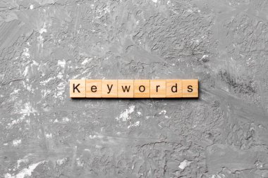 KEYWORDS kelime ahşap blok yazılı. Çimento masasındaki KEYWORDS metin desing, konsept.
