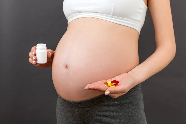 コピースペースとカラフルな背景で妊娠中の女性の手の中の薬のボトルとヒープの閉鎖 健康的な妊娠の概念 — ストック写真