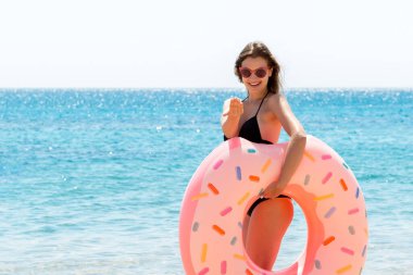 Sahilde deniz dibinde donut şişirilebilir yüzük tutan çekici bir kadının tam boy portresi. Mutlu yazlar..