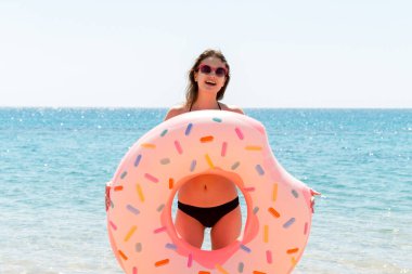 Güzel bir kadın plajda plajda plastik donut yüzüğüyle oynuyor..