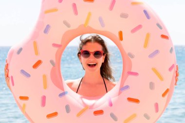 Güzel genç bir kadın, deniz dibinde donut şişirilebilir bir yüzükle poz veriyor..