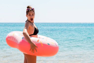 Donut lastiğinin içindeki şok olmuş genç kadın soğuk suyun içinde duruyor..