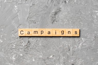 Tahta bloğa yazılmış kampanya kelimeleri. masa ve konsept üzerinde kampanya metni.