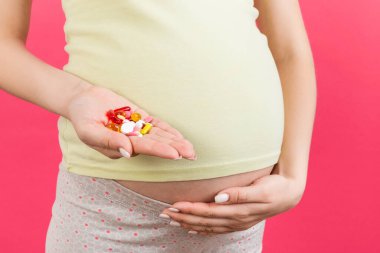 Hamile kadının elindeki renkli arka planda fotokopi alanı olan bir yığın hapı kapat. Sağlık hizmeti kavramı.