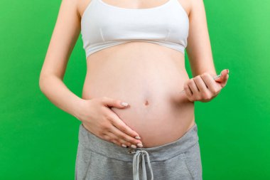 Hamile kadının karnına renkli arka planda fotokopi alanı ile insülin enjekte edişine yakın çekim. Hamilelik sırasında şeker kontrolü.