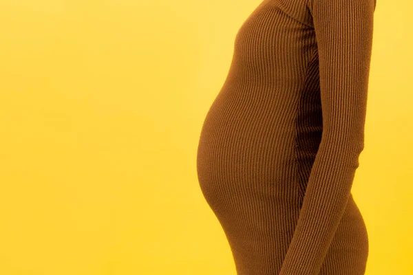Foto Recortada Abdomen Embarazada Vestido Marrón Con Fondo Amarillo Joven —  Fotos de Stock