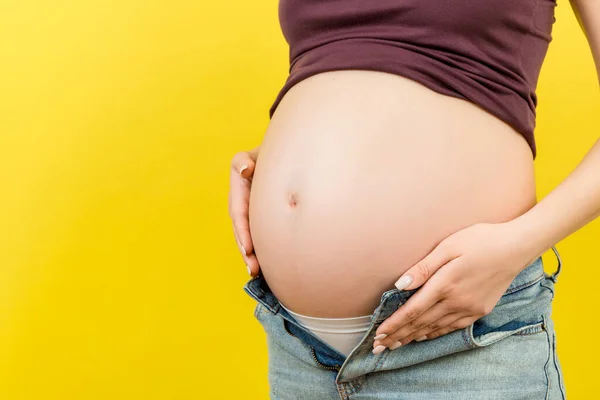 Primer Plano Mujer Embarazada Jeans Desabrochados Mostrando Abdomen Desnudo Fondo —  Fotos de Stock