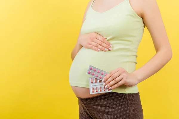 妊娠中の女性の手の中に水疱で薬の作物のイメージは コピースペースとカラフルな背景にあります 妊娠中のビタミン剤の服用 — ストック写真