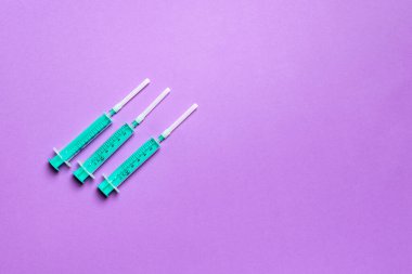 Renkli arkaplanda fotokopi alanı olan tıbbi enjeksiyon için üst sıradaki şırıngaların görüntüsü. Sağlık ve aşı kavramı.