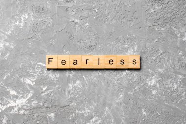 Tahta blokta korkusuzca yazılmış bir kelime. Çimento masasındaki korkusuz metin desing, konsept için.