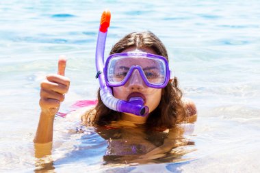 Genç kadın dalgıç maskesi takıyor ve denizde yüzme tüpü takıyor. Dalış ekipmanları.