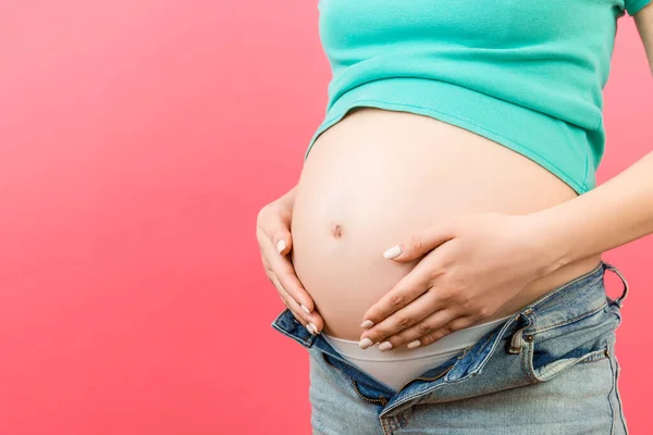 Primer Plano Mujer Embarazada Jeans Desabrochados Mostrando Abdomen Desnudo Fondo —  Fotos de Stock