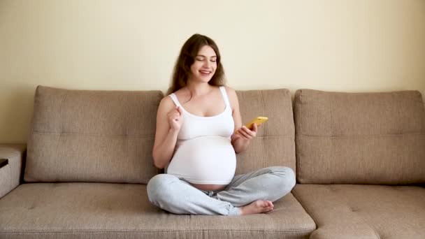 Schwangere Setzt Kopfhörer Auf Dem Sofa Auf Werdende Mutter Hört — Stockvideo
