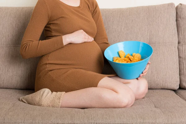 소파에 임신부를 가까이 그릇에서 감자칩을 즐긴다 임신중에 픕니다 — 스톡 사진