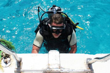 Scuba dalgıcı denizden yata tırmanıyor. Su altı dalışı.