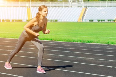 Genç sporcu bir pistte koşmaya hazırlanıyor. Kadın stadyumda yarışmaya hazırlanıyor. .