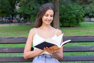 Şirin kız parkta bankta oturmuş ders kitabında bilgi topluyor. Kadın bir kitaba bakıyor ve ilginç bir şey arıyor..