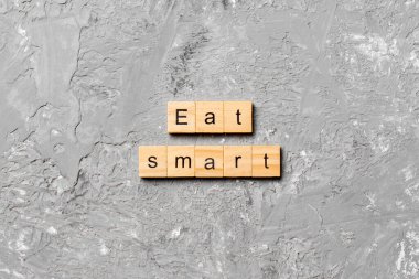 Ahşap blokta yazan akıllı kelimeyi ye. Üst görünüm konseptiniz için çimento masasında akıllı metin yiyin.