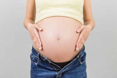 Açık kotlu hamile kadının renkli arka planda bebek karnını fotokopi aletiyle okşamasına yakın çekim. Bebek konseptini bekliyorum..