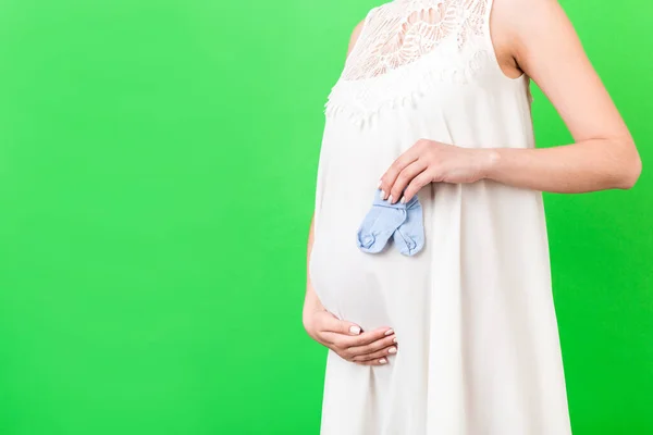 Hamile Bir Kadının Elinde Yeşil Arka Planda Karnına Yaslanmış Mavi — Stok fotoğraf