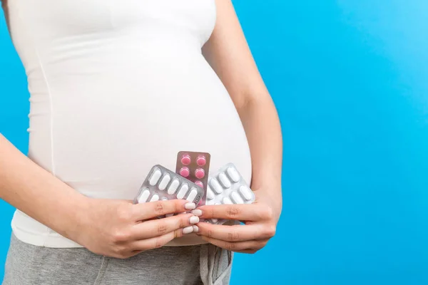 让孕妇在彩色背景下抱着产妇补品 并提供复印空间 水泡中的药丸怀孕期间的保健概念 — 图库照片