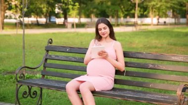 Yaz kenti parkında bankta oturmuş, not defterine notlar alan hamile bir kadın. Müstakbel anne hastaneye ya da dükkana bir liste yazar.