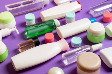 Renkli arka plandaki kozmetik ürünleri için farklı boyutlarda şişeler ve kavanozlar. Fotokopi alanı ile yüz ve vücut bakımı kavramı.
