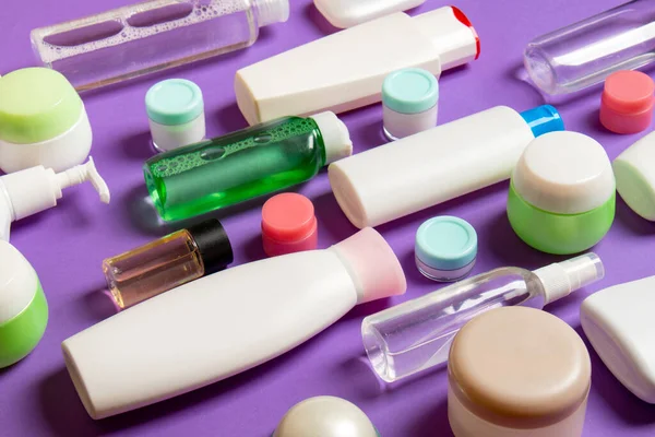 Renkli arka plandaki kozmetik ürünleri için farklı boyutlarda şişeler ve kavanozlar. Fotokopi alanı ile yüz ve vücut bakımı kavramı.