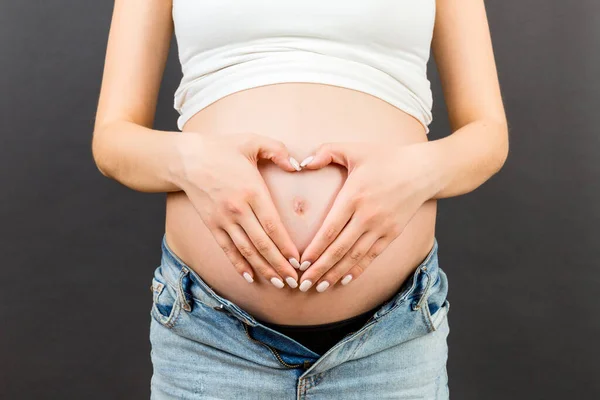Primer Plano Mujer Embarazada Vaqueros Abiertos Haciendo Corazón Vientre Fondo —  Fotos de Stock