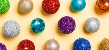 Sarı arka planda renkli Noel baloları afişi. Yeni yıl konsepti.